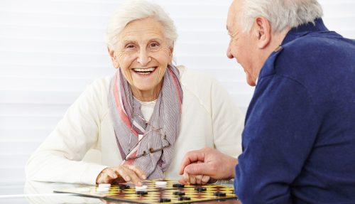 Happy senior couple playing checkers in a retirement home